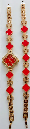 Gold-tone watch bracelets with red four-leaf clover motifs and a central round watch face, displayed on a white background.