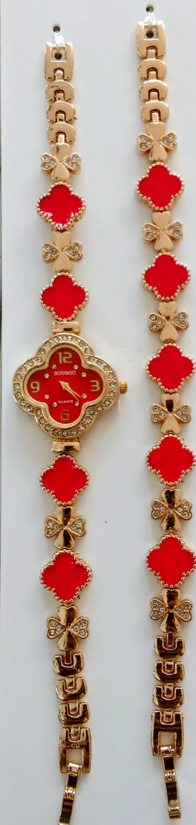 Gold-tone watch bracelets with red four-leaf clover motifs and a central round watch face, displayed on a white background.